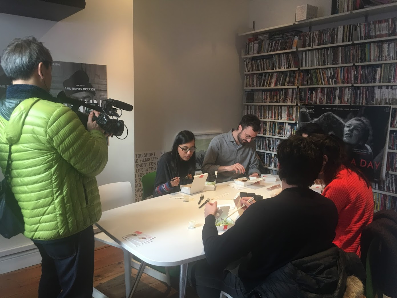 People eating lunch boxes during an office lunch filming scene